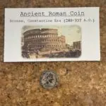 Roman coin side by side with a descriptive card dating 280-337 A.D.